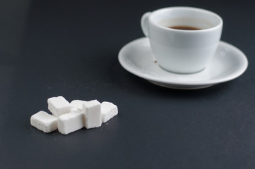 White coffee cup with sugar cubes isolated on a black background