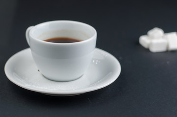 White coffee cup with sugar cubes isolated on a black background
