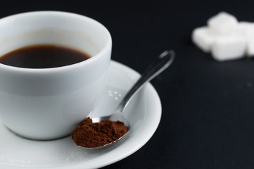 White coffee cup with sugar cubes isolated on a black background