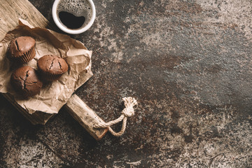 Coffee beans with coffee and muffins on dark textured background.