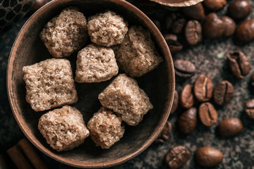 Sugar with coffee beans on dark textured background.