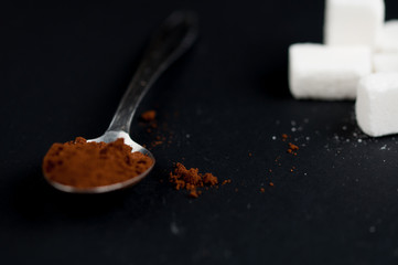 Coffee spoon and sugar cubes isolated on a black background