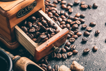 Coffee with coffee grinder and coffee beans on dark textured background.