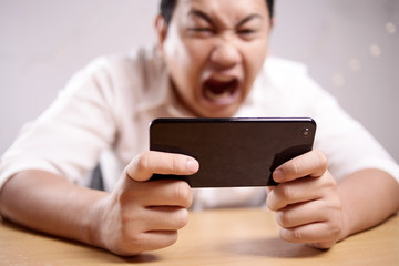 Funny Young Asian Guy Playing Games on Tablet
