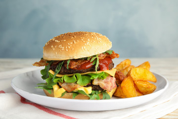 Tasty burger with bacon and fried potatoes on plate