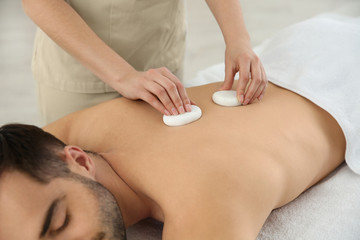 Obraz na płótnie Canvas Man receiving hot stone massage in spa salon, closeup