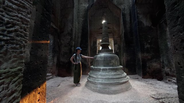 Sliding view of caucasian woman with backpack exploring and touching Preah Khan and central stupa. It's a temple at Angkor, Cambodia, built in 12th century for King Jayavarman VII to honor his father