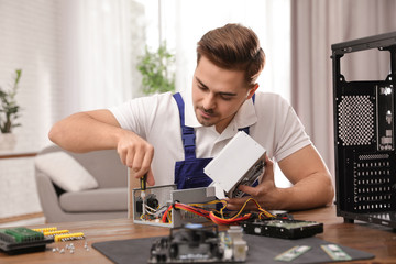 Male technician repairing power supply unit at table indoors