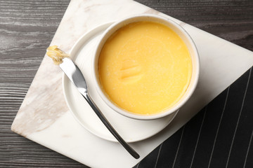 Flat lay composition with bowl of melting butter on wooden table