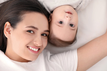 Portrait of mother with her cute baby lying on bed, top view