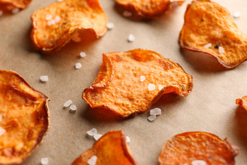 Sweet potato chips with salt on color background, closeup