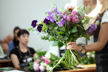 Female florist explain to students how to create bouquet at workplace. Floristics workshop.  Making beautiful flower bouquets and floral decorations. - obrazy, fototapety, plakaty