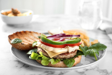 Plate with tasty burger on table. Space for text