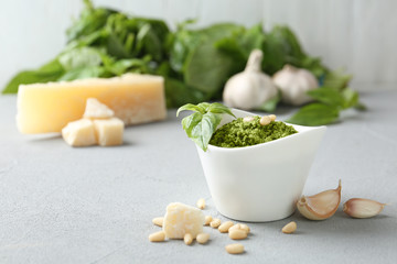 Composition with bowl of tasty pesto sauce on grey table. Space for text