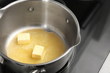 Fototapeta na wymiar Saucepan with melting butter on electric stove, closeup
