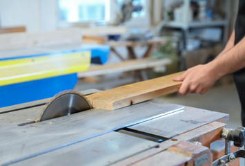 Working man using circular saw at carpentry shop, closeup