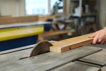 Working man using circular saw at carpentry shop, closeup