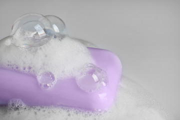 Soap bar and foam on light background, closeup