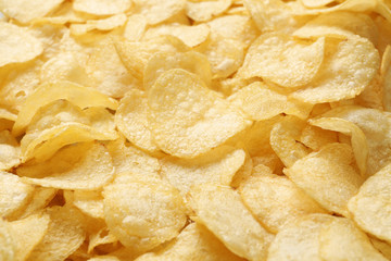 Pile of crispy potato chips as background, closeup