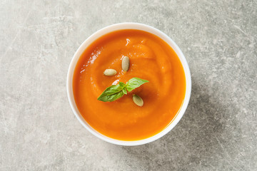 Bowl of tasty sweet potato soup on grey background, top view