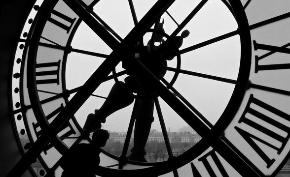 Man looking through giant clock window black and white architecture 