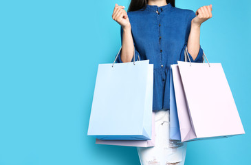 Woman with blank paper bags against color background, closeup. Space for text