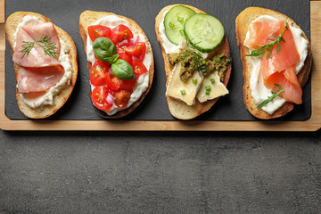 Board with different tasty bruschettas on grey table, flat lay. Space for text