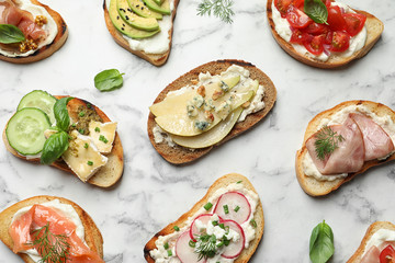 Different tasty bruschettas on marble background, flat lay