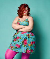 Annoyed or very picky plus-size overweight lady in sunglasses and sundress with her arms crossed waits for something on mint