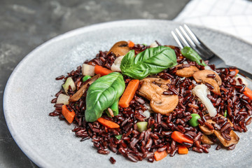 Plate of brown rice with vegetables on table, closeup