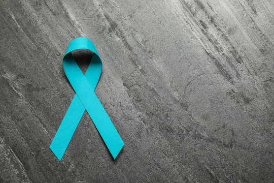 Teal ribbon on grey background, top view. Space for text
