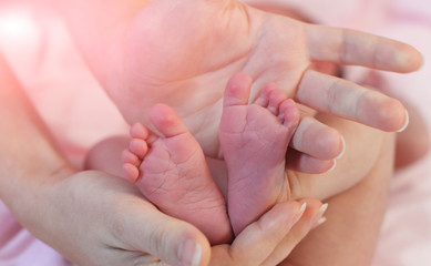 mother holds hands on the feet 