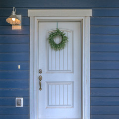 White door with wreath against blue exterior wall © Jason