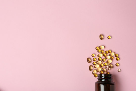 Bottle with cod liver oil capsules on color background, flat lay. Space for text