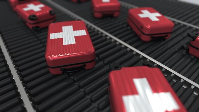 Many travel suitcases featuring flag of Switzerland on roller conveyer. Swiss tourism conceptual animation