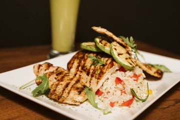 Grilled chicken with rice and vegetables by the glass of juice