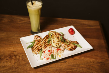 Grilled chicken with rice and vegetables by the glass of juice