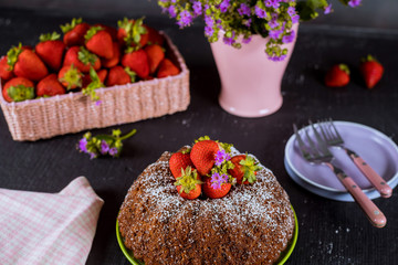 Homemade bundt cake with fresh strawberries ,plate ,vase with flowers.