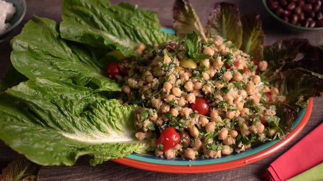 High turning shot of beautiful platter of tabbouleh garnished with lettuce on a distressed wood table set against a blue background.