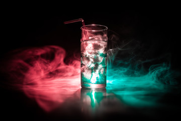 Cocktail glass splashing on dark toned smoky background or colorful cocktail in glass. Party club...
