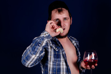 Cute man in a blue shirt, naked body, blue background, a glass of wine and a banana.
