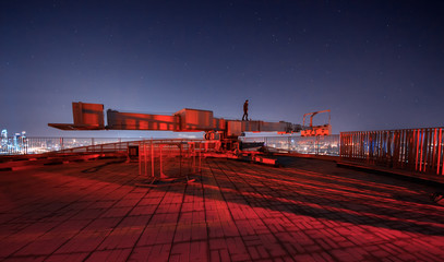 lonely man on a crane on the roof of a skyscraper on the background of the starry sky in Moscow