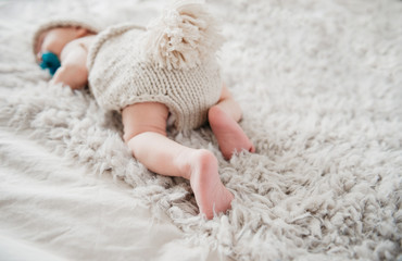 Adorable newborn is sleeping butt -up in cute knitted outfit on fluffy blanket