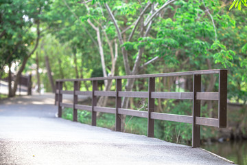 A blurred background of wooden bridge rails that cross the river in the park, preventing people from falling in case of running, jogging or cycling.