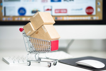 Concept of online shopping or e-commerce with miniature paper boxes on shopping trolley against...