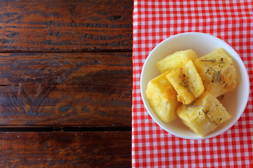 boiled and fried cassava (mandioca) in ceramic bowl on rustic wooden table