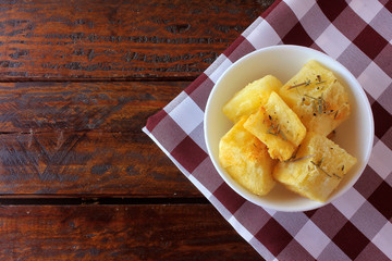 boiled and fried cassava (mandioca) in ceramic bowl on rustic wooden table