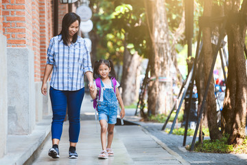 Back to school. Cute asian pupil girl with backpack holding her mother hand and going to school