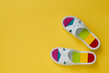 Colorful women's flip-flops on a yellow background. The concept of a holiday by the sea. Flat lay.
