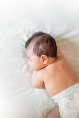 cute newborn baby is sleeping on white bed